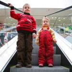 Children standing side by side on an escalator step
